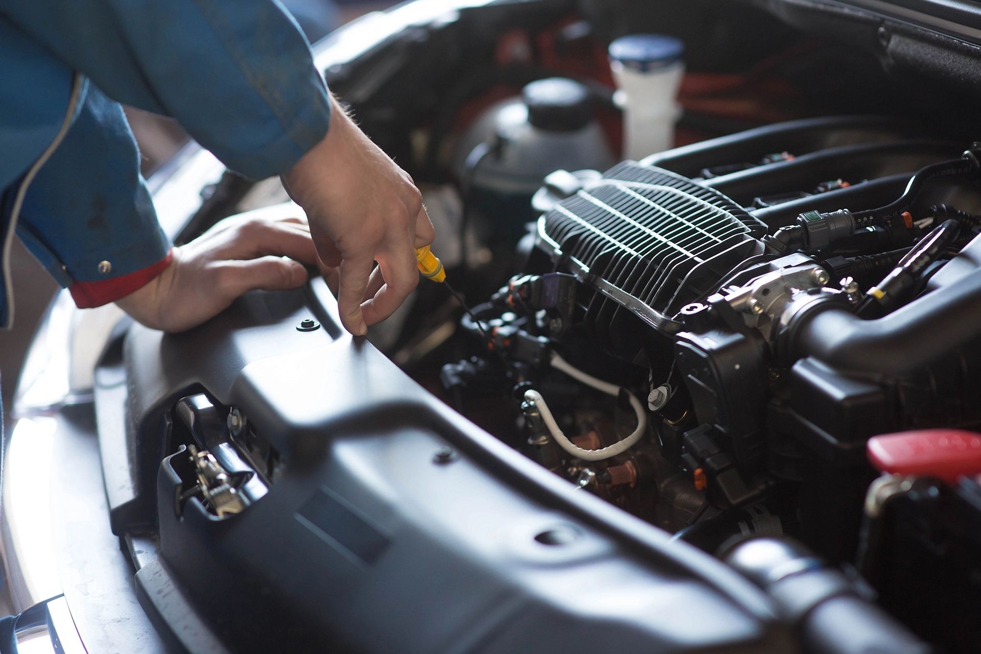 Mechanic performing vehicle maintenance under the hood